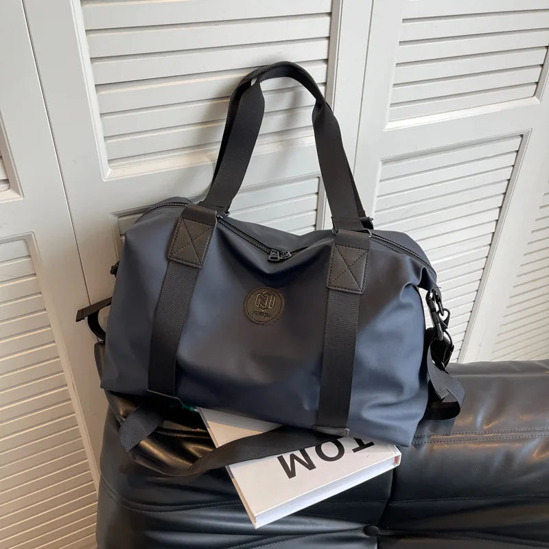 A dark gray Versatile Oxford Cloth Travel Tote Bag resting on a black leather surface.