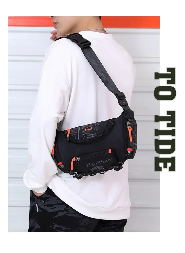 Eine Person trägt eine schwarze taktische Brusttasche mit orangefarbener Akzent auf einem weißen Langarmshirt.