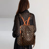 A woman is shown from the back wearing a brown genuine leather backpack with a leopard print shirt and a black skirt.