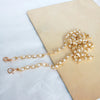 Gold adjustable chain strap made of small white pearls lying on a beige surface.