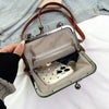 A vintage style women's shell handbag with a silver frame and brown leather crossbody strap is shown open.