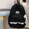 Black polka dot nylon travel backpack with a laptop compartment being held by a person.