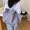 A person holds a gray and white leopard print canvas tote bag against a light background.