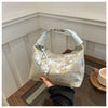 A light blue embroidered crossbody shoulder bag resting on a wooden surface.