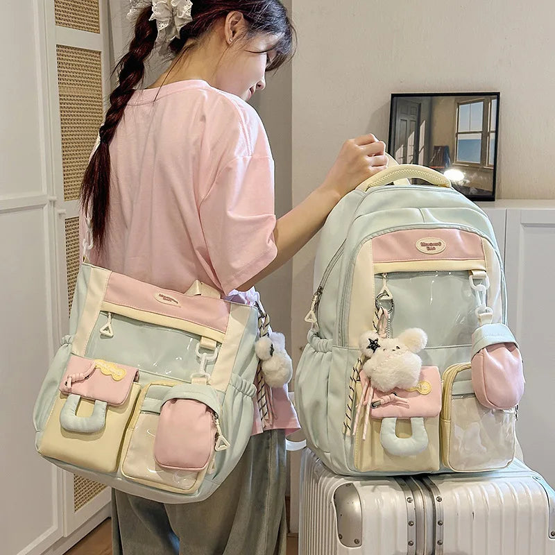A pink and white kawaii backpack with a fluffy bear charm is being held by a girl in a light room.