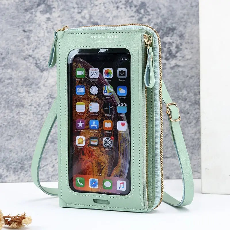 Hellmintgrüne multifunktionale Crossbody-Handytasche mit goldfarzger Zipper und Trageriem, vor grauem Hintergrund.