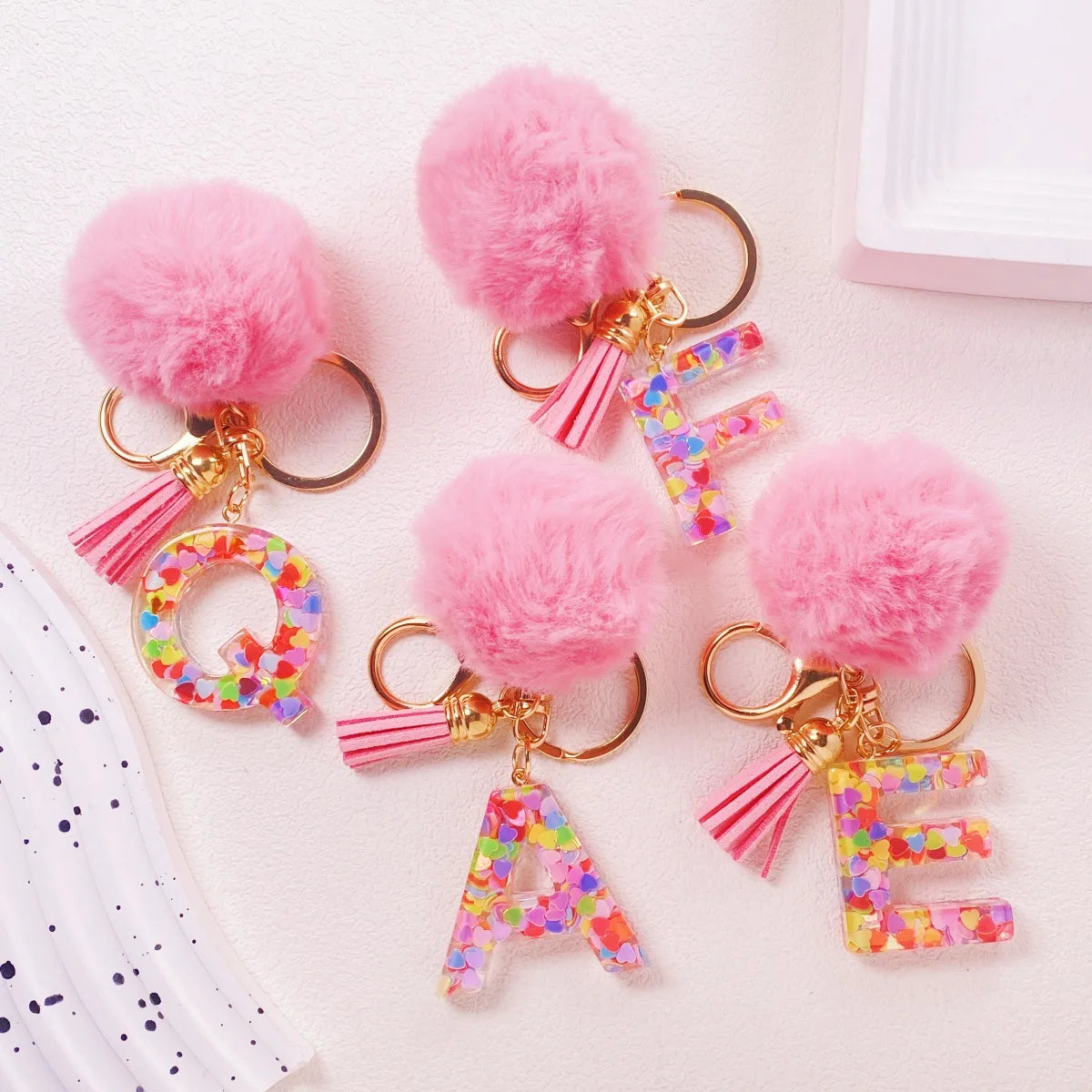 Pink fuzzy pom-pom initial letter keychain charms in shiny resin for bags and backpacks