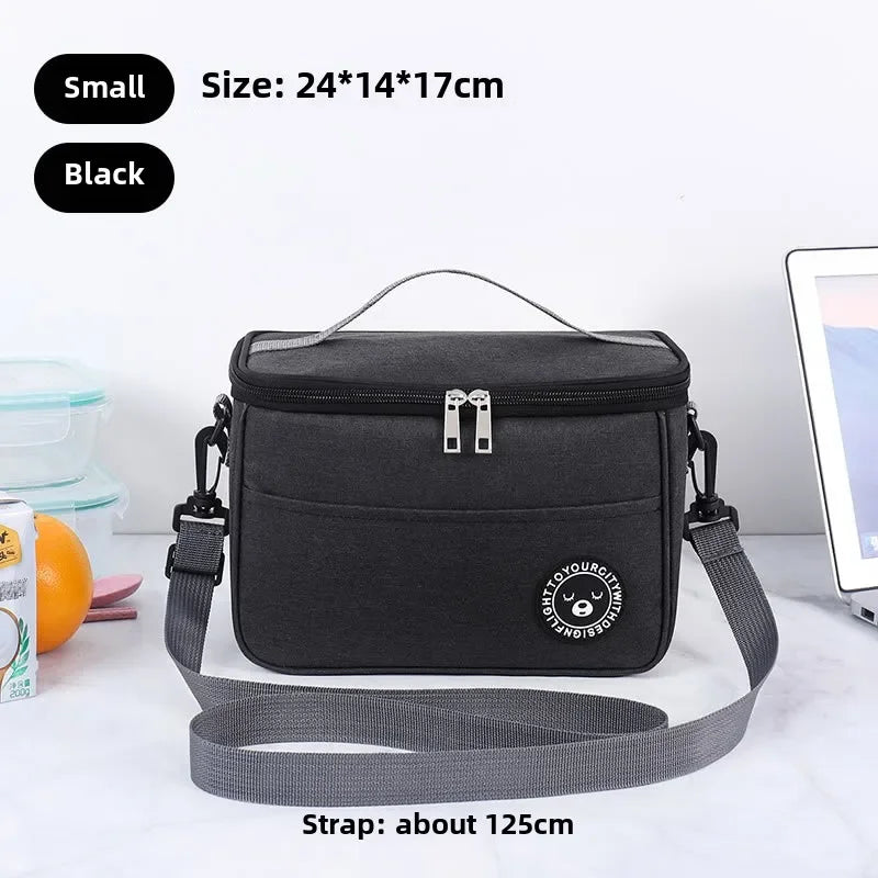 Black insulated portable lunch bag with a gray shoulder strap shown on a white surface.