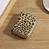 A compact wallet made of leopard print PU leather resting on a wooden surface.