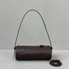 A dark brown vintage cow leather cylinder shoulder bag with a thin black strap is displayed against a light background.