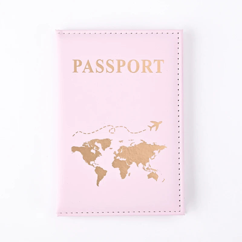A pink passport holder wallet with gold lettering and a gold world map design.