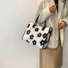 A woman holds a black and white leopard print faux fur designer shoulder tote bag against a white background.