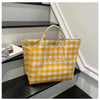 A yellow and white checkered transparent waterproof PVC tote bag is displayed on a dark shelf.