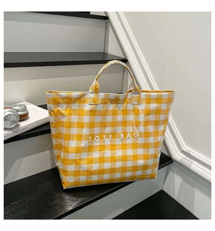 A yellow and white checkered transparent waterproof PVC tote bag is displayed on a dark shelf.