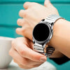 A person is wearing a stainless steel expansion watch with a black face and silver band on their wrist.