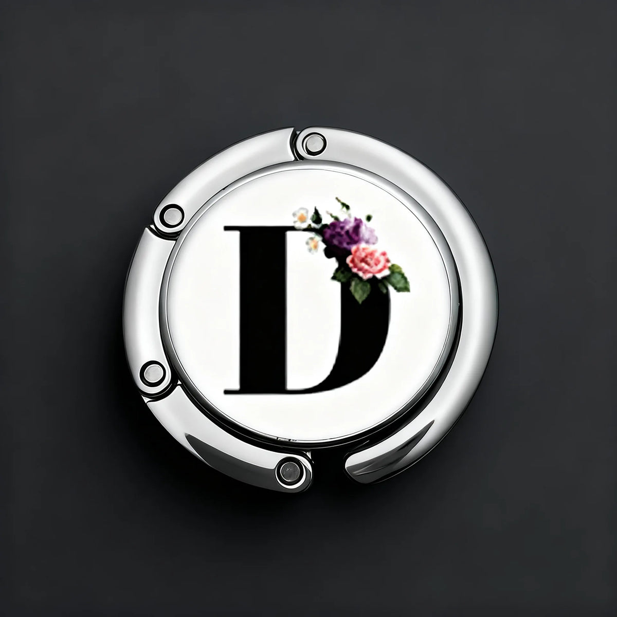 A silver, round letter D with a floral design is shown on a dark background.