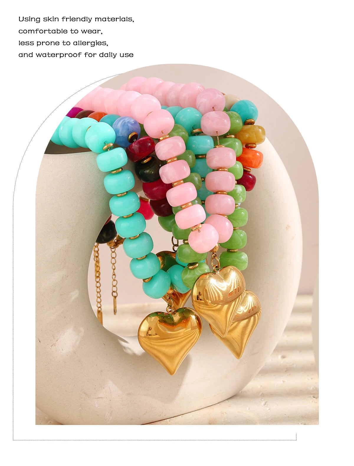 A colorful heart charm bead necklace featuring pink, blue, and green resin beads on a gold chain.