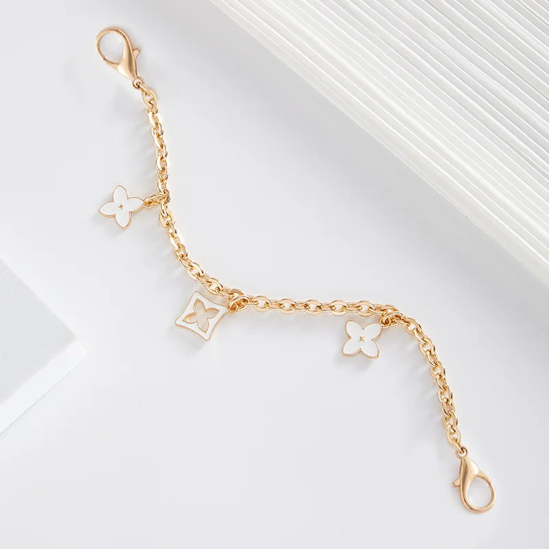 A delicate gold chain with small flower charms, displayed against a white background.