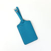 A teal PU leather luggage tag with a silver clip attached to a blue strap.