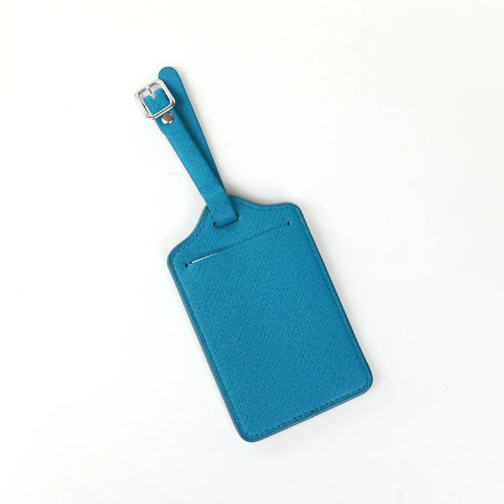 A teal PU leather luggage tag with a silver clip attached to a blue strap.