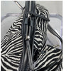 Nahaufnahme einer schwarz-weißen Zebra-Print-Canvas-Crossbody-Tasche mit schwarzem Reißverschlussdetail.