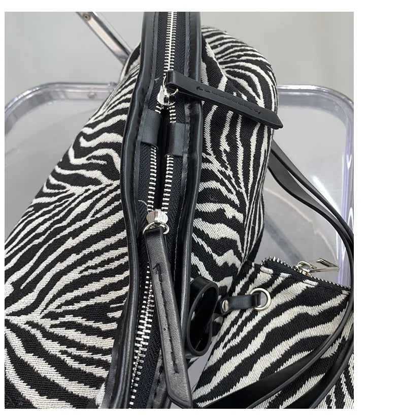 Nahaufnahme einer schwarz-weißen Zebra-Print-Canvas-Crossbody-Tasche mit schwarzem Reißverschlussdetail.