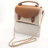 Tan und cremefarbener Leder-Crossbody-Tasche mit goldfargener Kettchenriemen auf einer weißen Box