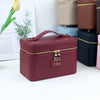 A maroon PU leather makeup bag with gold zippers and a leather tag reading Lisa, displayed next to other colored bags.