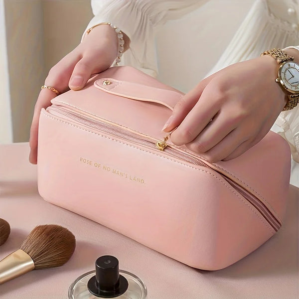 Une pochette de maquillage de luxe rose est tenue par des mains, avec un pinceau de maquillage et un produit noir visible à p