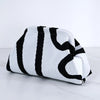 Bolso de crochet a rayas blanco y negro, doblado sobre una superficie de mármol.