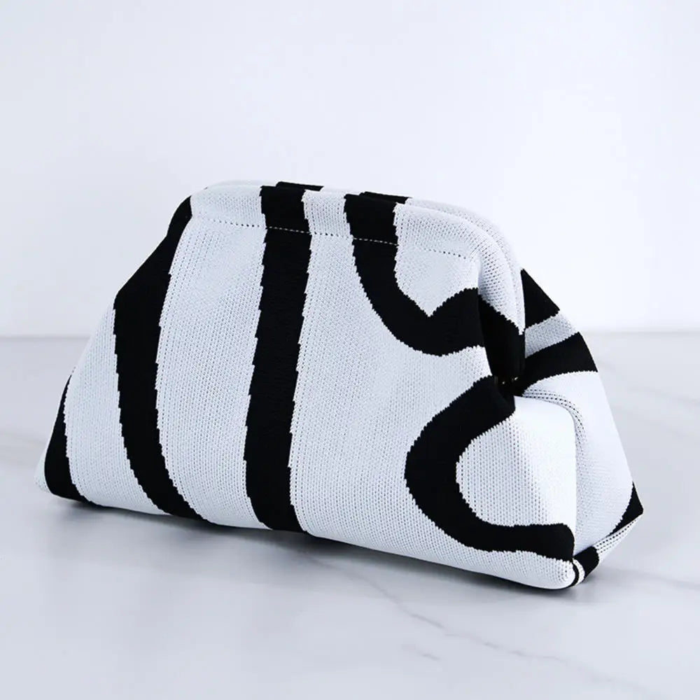 Bolso de crochet a rayas blanco y negro, doblado sobre una superficie de mármol.