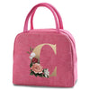 A pink insulated canvas lunch bag featuring a large gold letter C and floral accents.