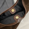 Close-up of a brown suede slouchy shoulder bag interior showing hardware and lining.