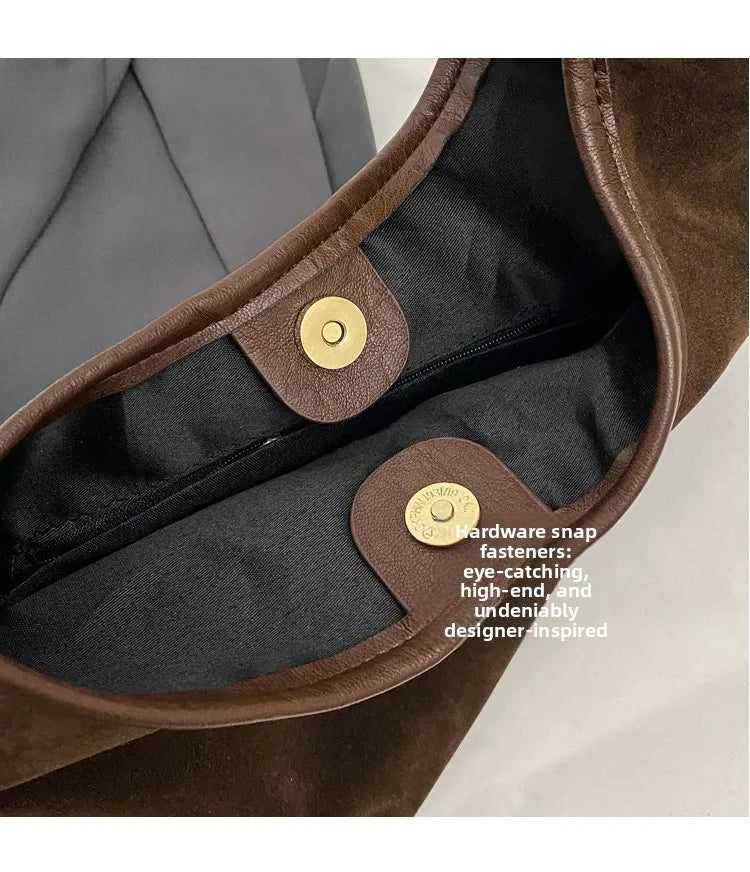 Close-up of a brown suede slouchy shoulder bag interior showing hardware and lining.