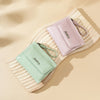 A light pink leather mini wallet with a cord is placed on a wooden surface.