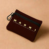 A dark maroon zippered pouch with gold lettering for a fashion show event.