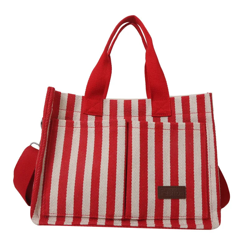 Sac bandoulière en toile rayée rouge et blanc avec anses en tissu rouge.