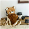 A brown red panda plush toy is displayed next to a black camera lens and leather straps on a wooden surface.