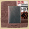 A dark coffee colored genuine leather passport wallet with card holders resting on a brown fabric.