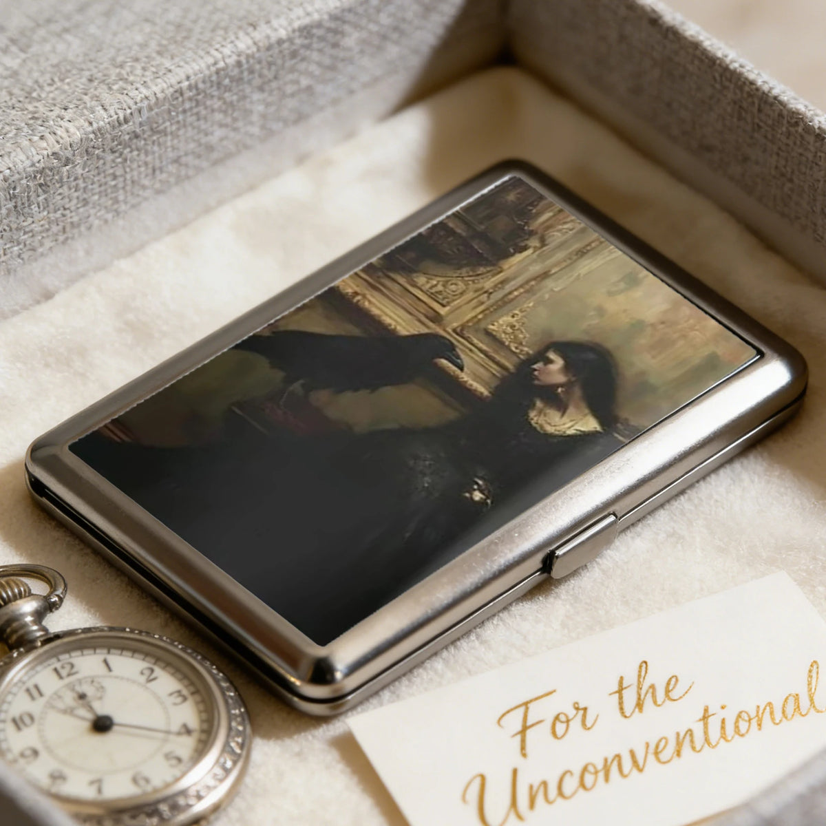 An Art Deco metal card holder with a dark photograph resting in a light-colored box.