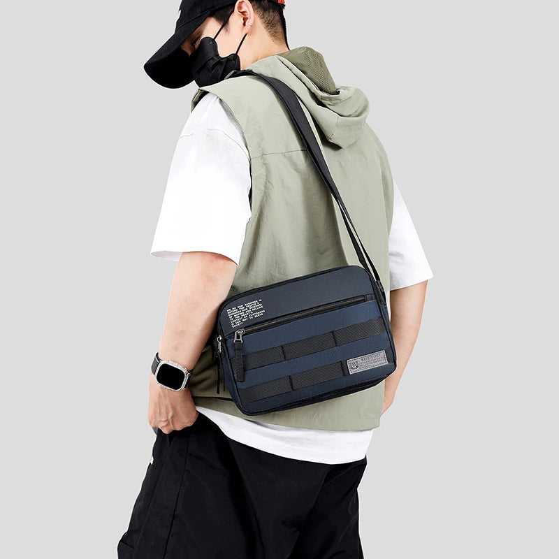 A person wearing a black mask and a white shirt carries a dark blue nylon shoulder bag over their shoulder.