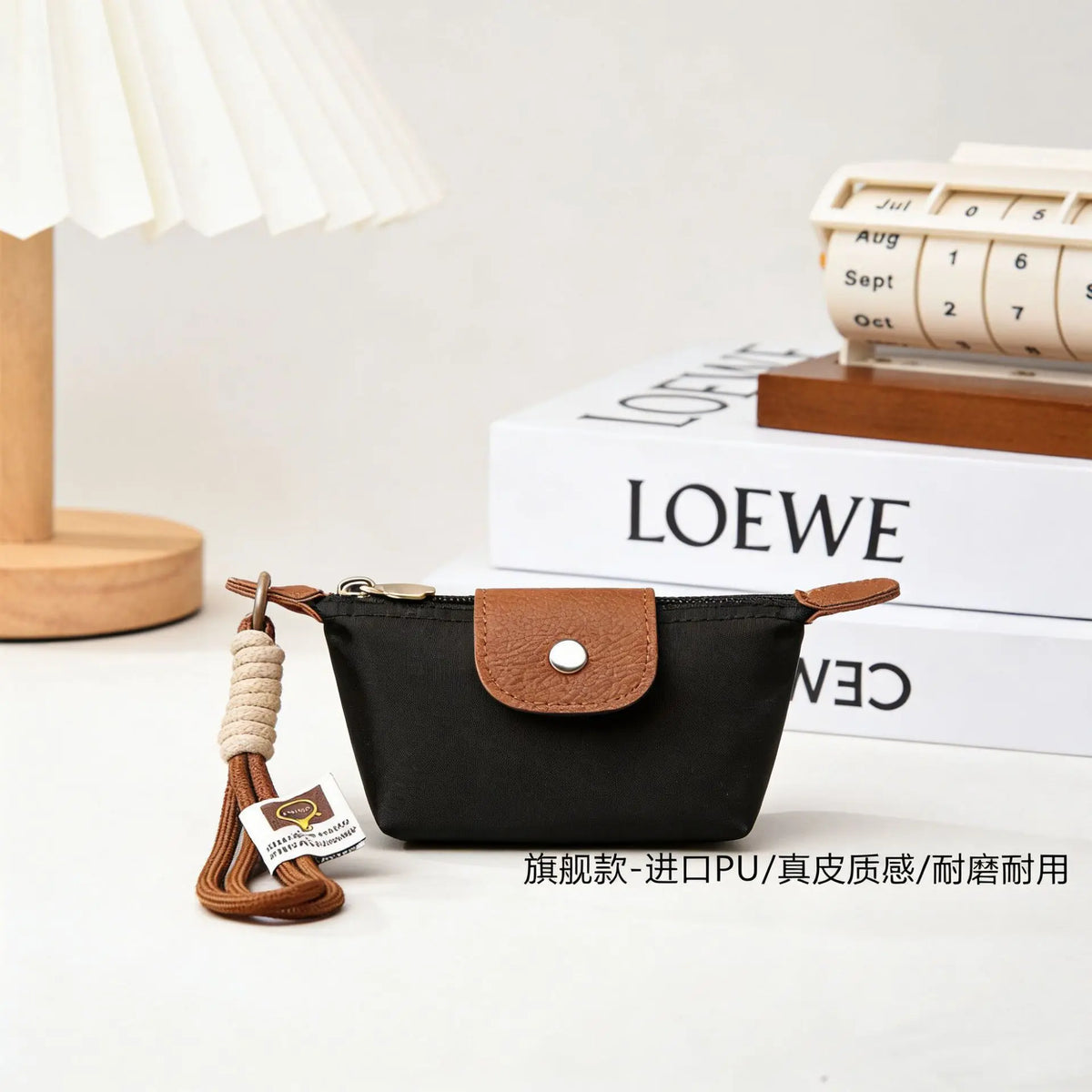 Black compact coin purse with a brown faux leather flap and braided keychain strap