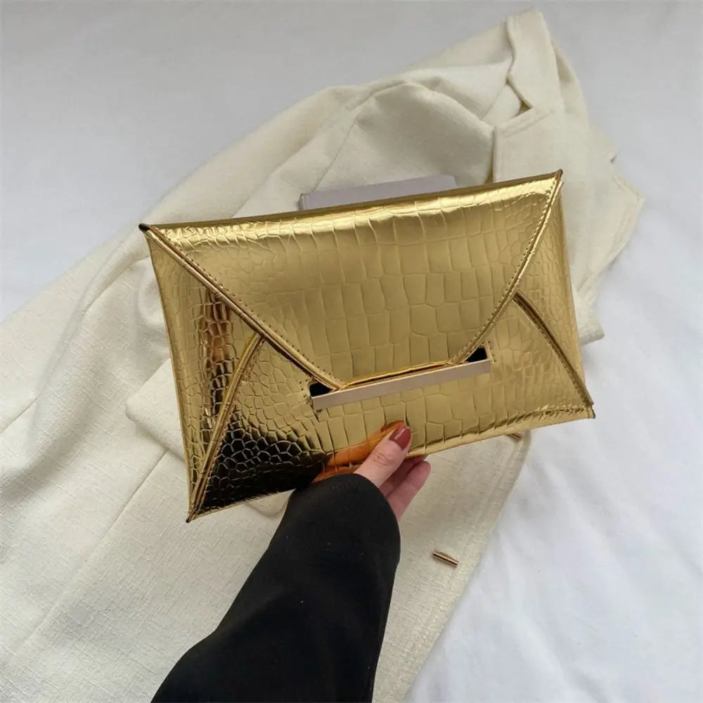 A gold crocodile pattern coin purse clutch is shown being held against a light beige fabric background.