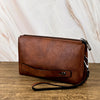Portefeuille pochette en cuir marron rétro pour homme sur une surface en bois.