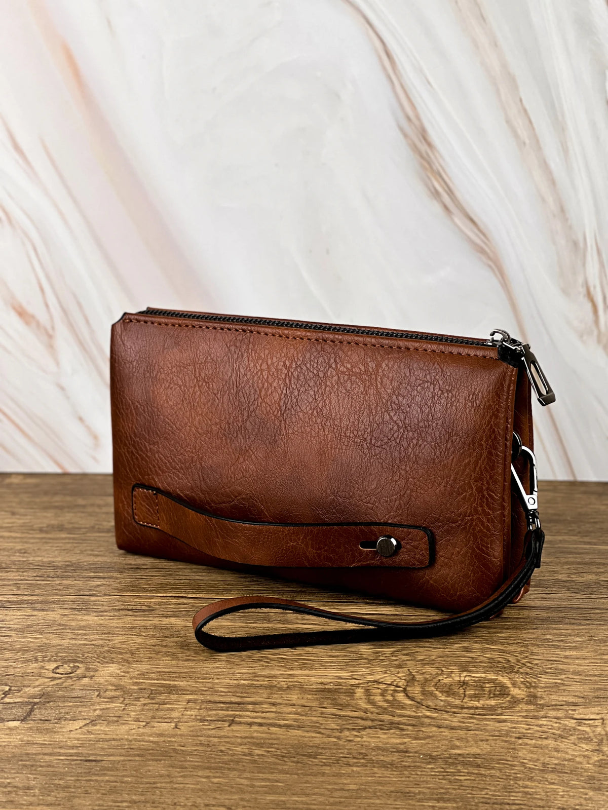 Portefeuille pochette en cuir marron rétro pour homme sur une surface en bois.