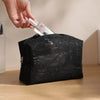 A hand is opening a black lace mesh cosmetic and jewelry organizer bag.