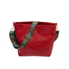 A deep red leather crossbody hobo bag with a patterned blue and gold strap.