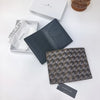 A dark gray geometric print passport wallet and a white tissue are displayed on a white surface.