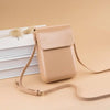 A beige vintage PU leather crossbody bag with a thin strap resting on a stack of white books.