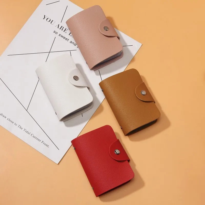 A collection of four premium PU leather wallets in shades of pink, beige, and red resting on a white paper background.